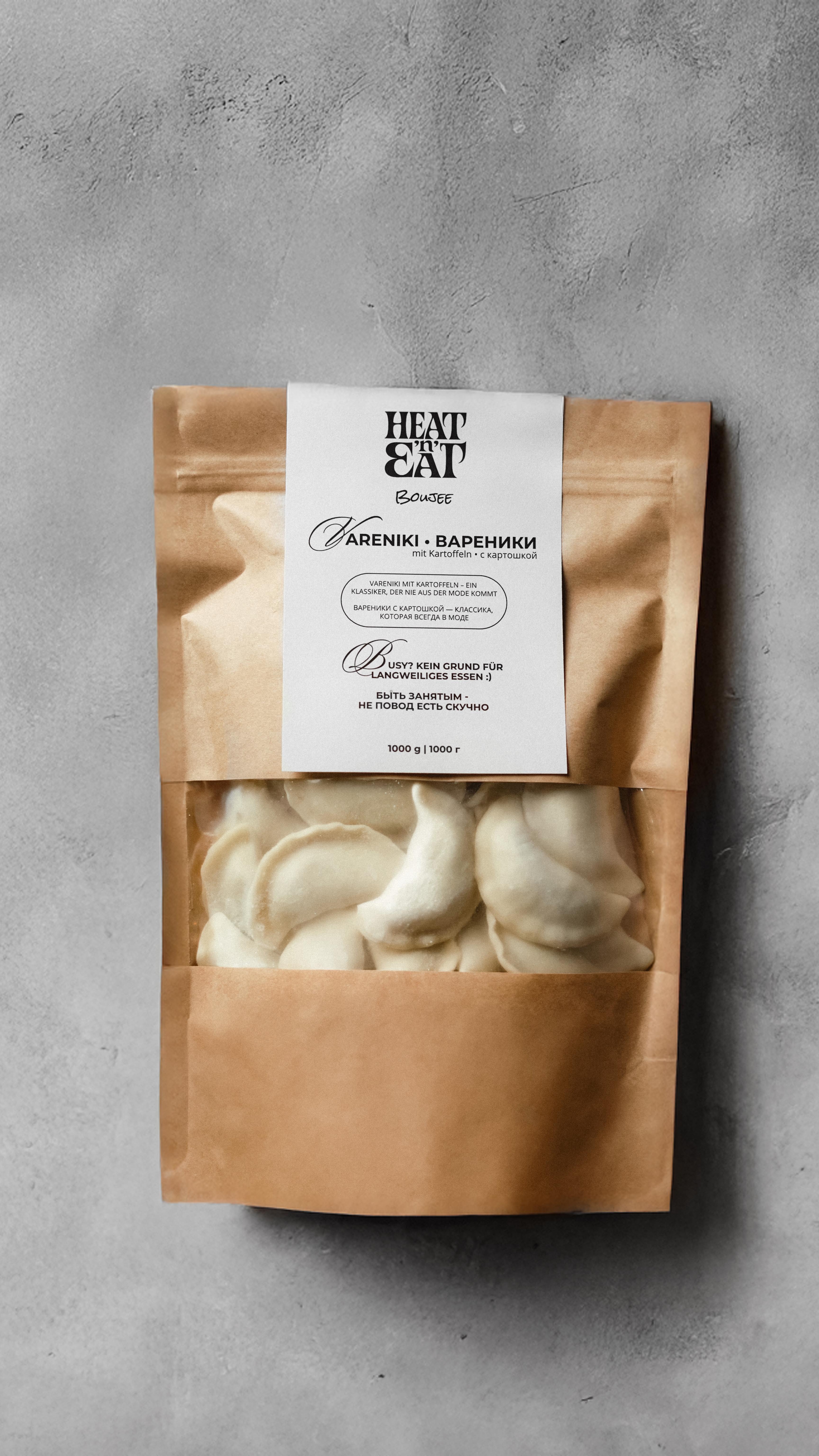 Eine braune Papiertüte mit hellen Teigtaschen und weißem Etikett auf grauem Hintergrund